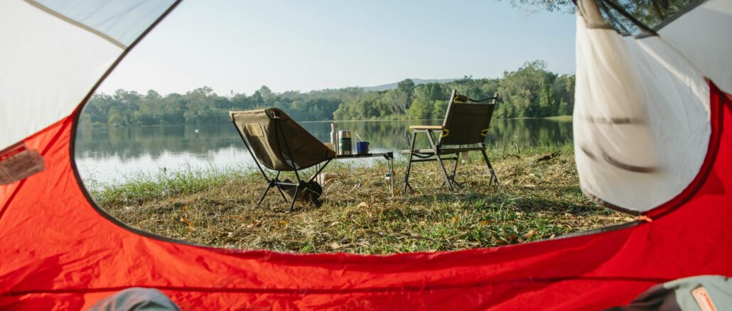 Open camping tent door facing chairs and norris lake on sunny morning