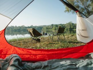 Open camping tent door facing chairs and norris lake on sunny morning