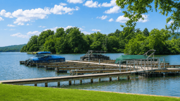 Floating boat docks on a calm lake, with covered pontoons and a tree-lined shore under a blue sky.